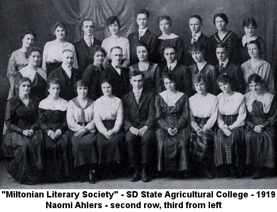 Black and white college yearbook photo of three rows of college-age men and women standing and sitting before a drapery backdrop.
